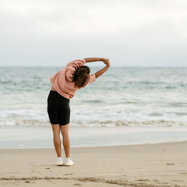Person stretching outdoors during sunrise, feeling energized.